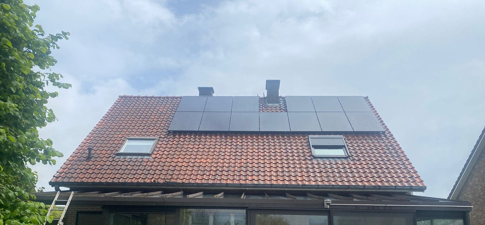 The same roof with cleaned red tiles, solar panels and roof windows