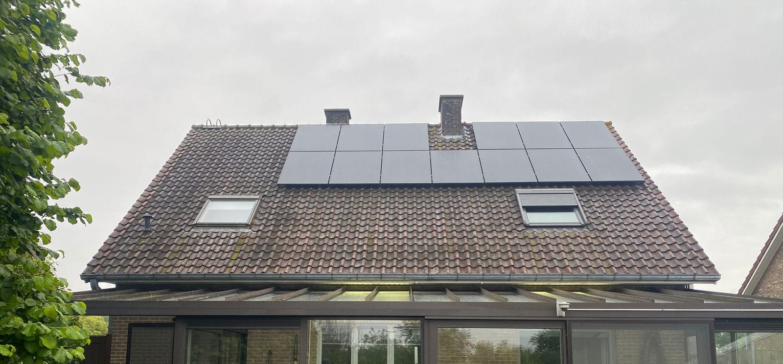 Dark-tiled roof carrying solar panels and two roof windows