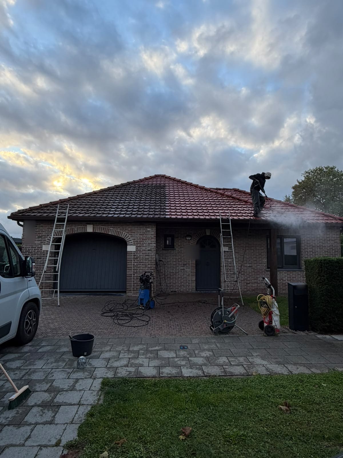 Bungalow with a tiled roof half cleared of moss, a member of our team at work on the roof