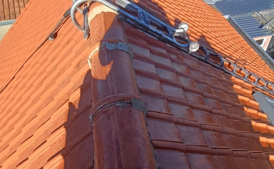 Clean red tile slopes on each side of the ridge, roof ladder and roof window