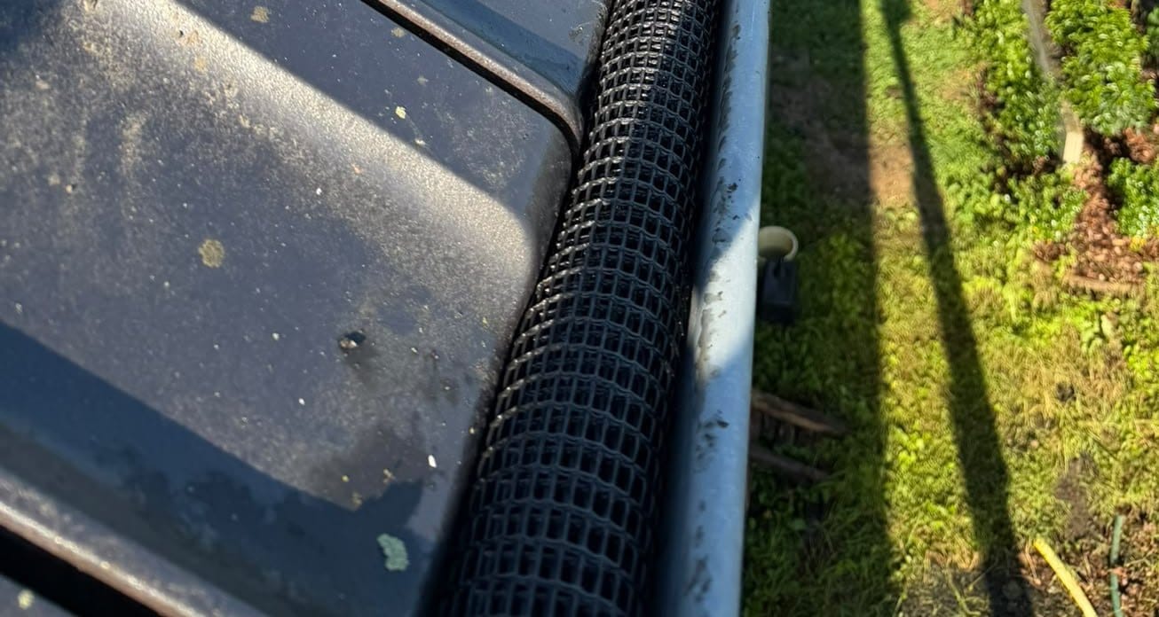 Gutter covered with a black mesh at the foot of a slope of tiles, seen from above, in Jamioulx