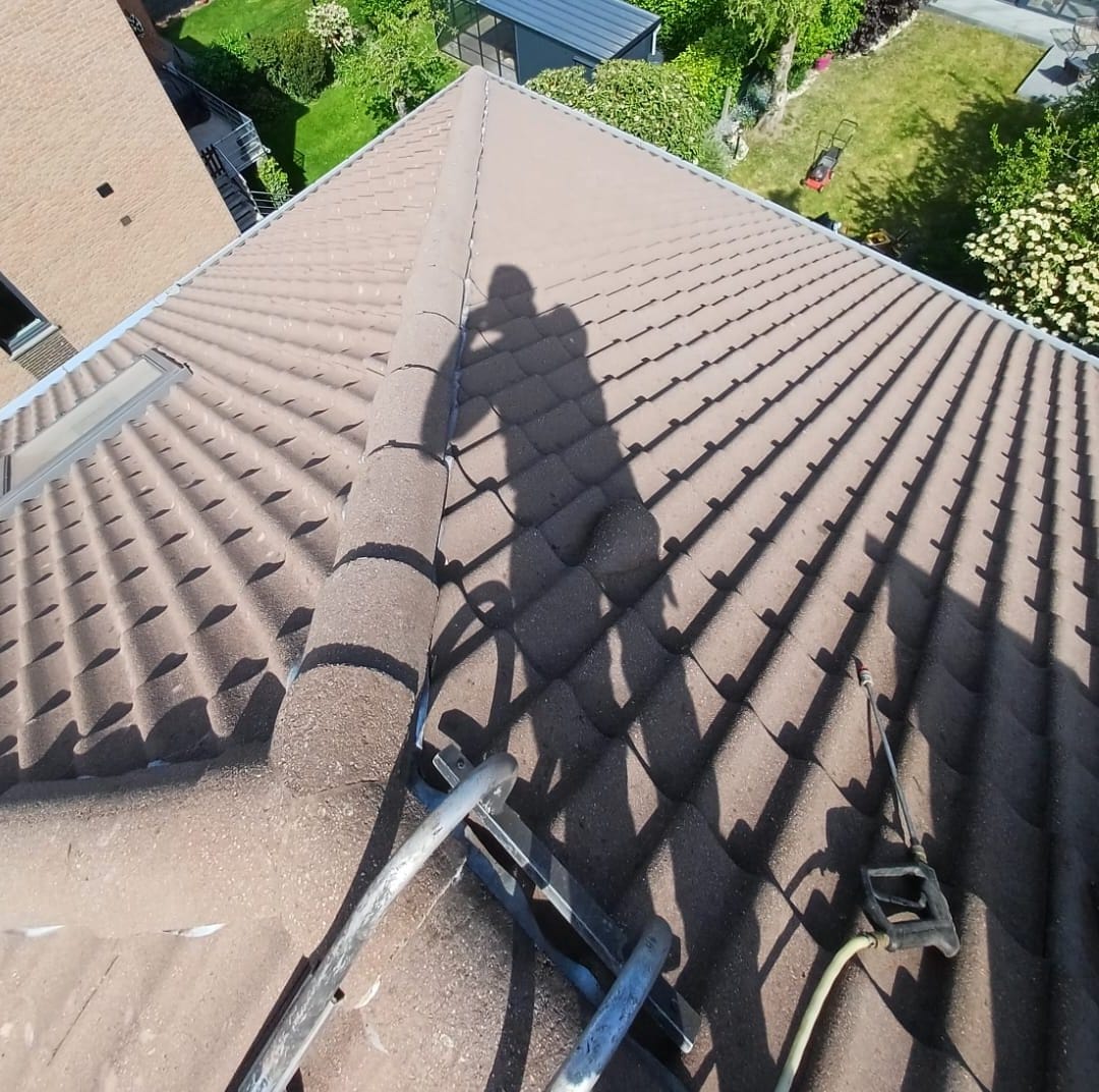 Two slopes of brown tiles meeting at the ridge, a roof window on the left, gardens in the distance