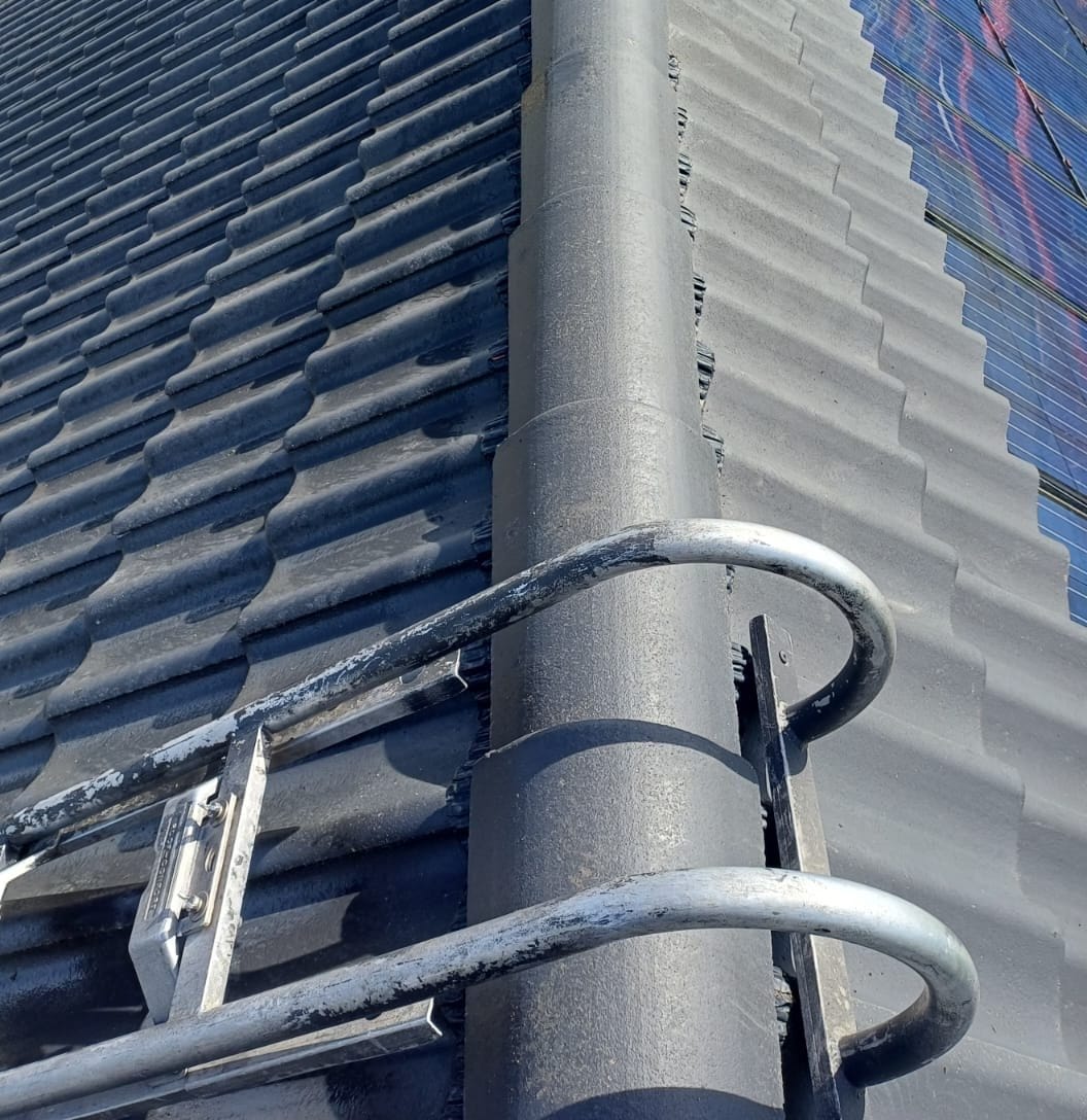 Grey ridge surrounded by dark, clean tiles, roof ladder set on it, solar panels at the top right